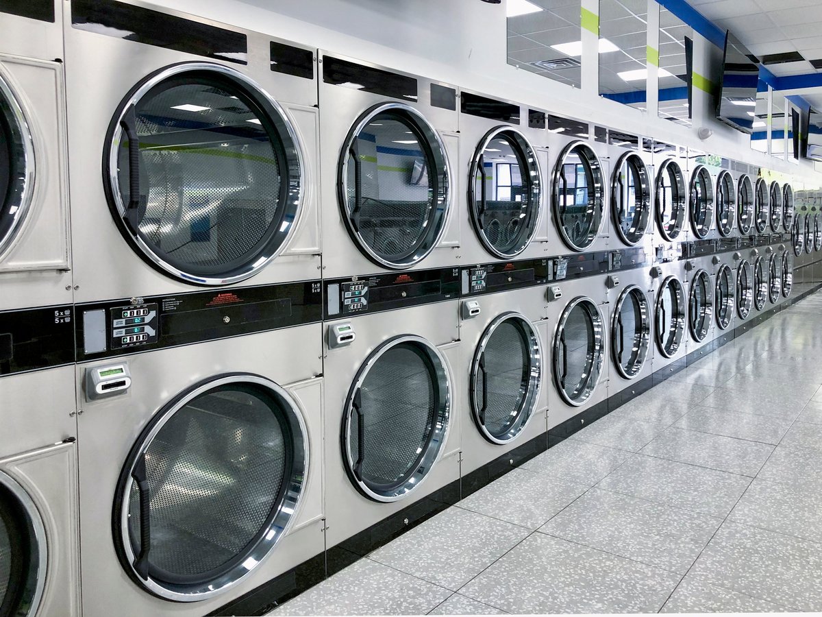 Commercial laundry equipment with washing machines and dryers in a bright facility